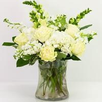 A gathering vase filled with assorted white flowers.